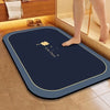 A dark blue diatomite bath mat with a gold trim is placed on a tiled floor next to a bathtub.