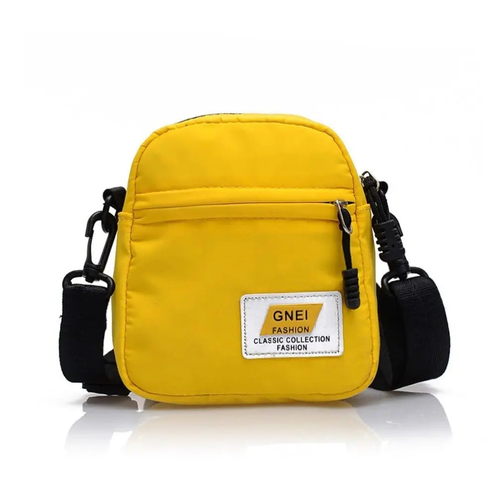 Yellow mini canvas crossbody bag with black strap and a white label on the front