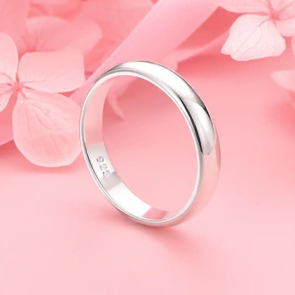 Bague en argent sterling polie sur fond rose avec des éléments floraux doux.