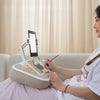 A woman uses a 360° rotatable phone stand and lap desk for viewing while relaxing.