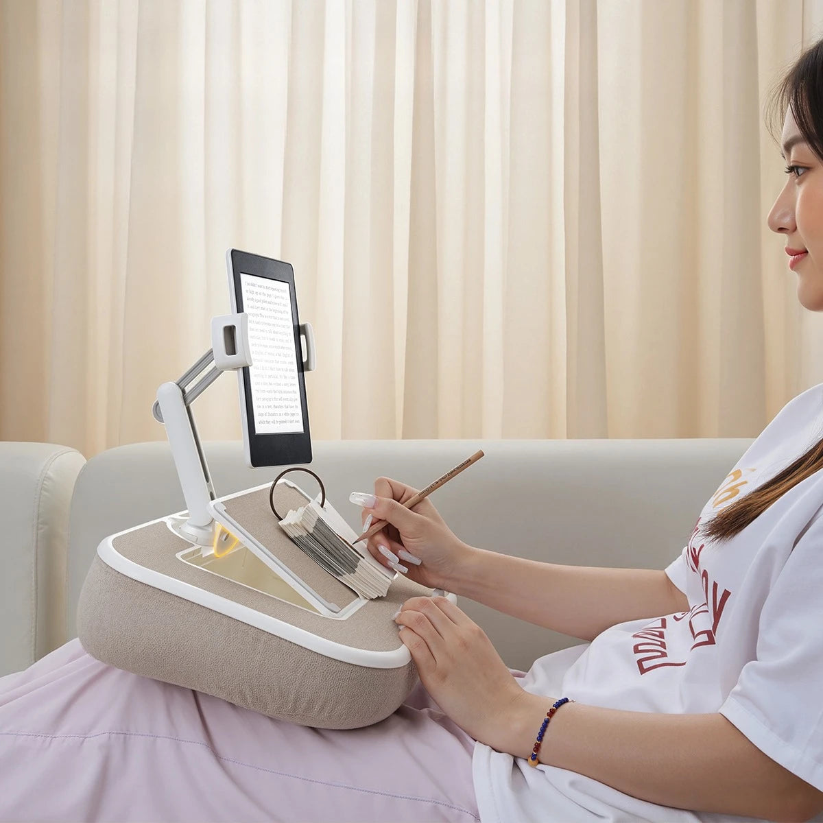 A woman uses a 360° rotatable phone stand and lap desk for viewing while relaxing.