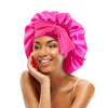 A woman wearing a bright pink satin sleeping bonnet with an adjustable tie.