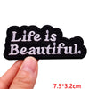 Black embroidered iron-on letter patch with the text Life is Beautiful