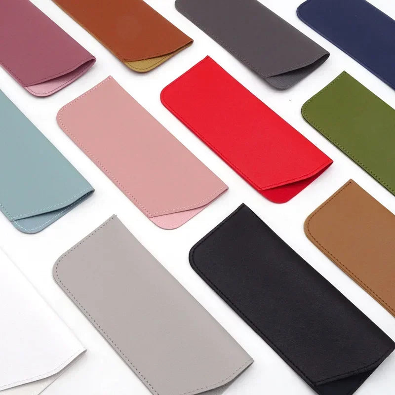 Colección de diversas fundas protectoras para gafas de cuero PU de varios colores sobre fondo blanco.