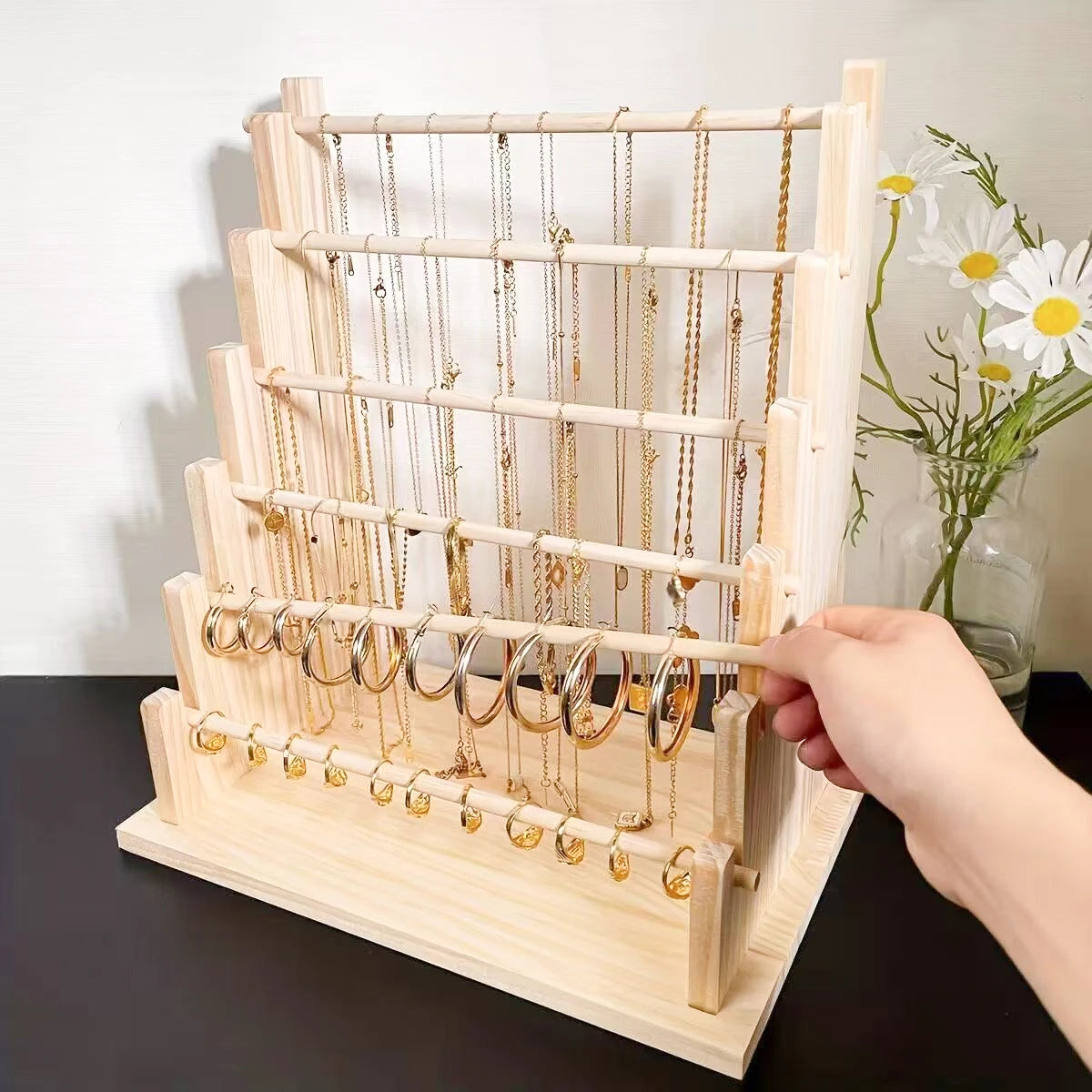 A wooden ladder jewelry organizer displaying multiple tiers of delicate gold necklaces and chains.