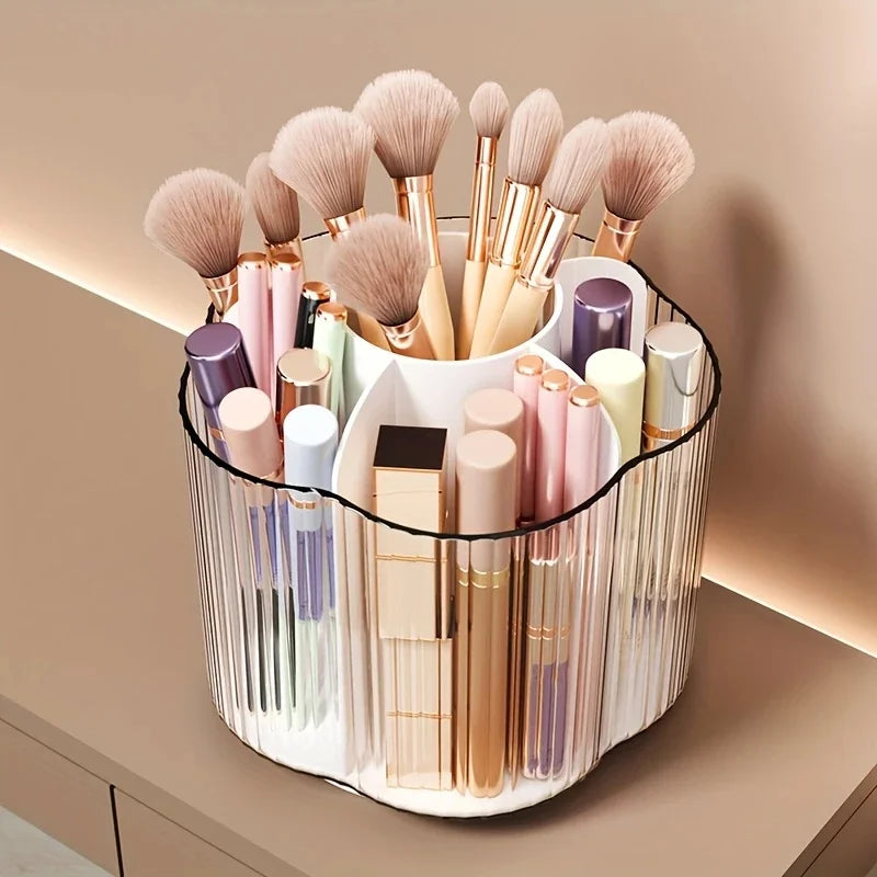 A clear acrylic rotating makeup brush holder with six compartments filled with various makeup brushes and tools.