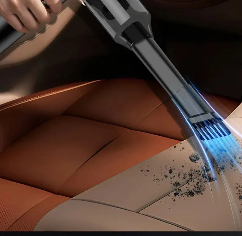 A handheld vacuum cleaner is cleaning dust from a car's leather interior surface.