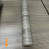 Roll of self-adhesive wood grain cabinet and furniture refacing film on a wooden surface.