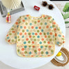 A light yellow baby feeding smock with a pattern of multi-colored polka dots displayed on a white table.