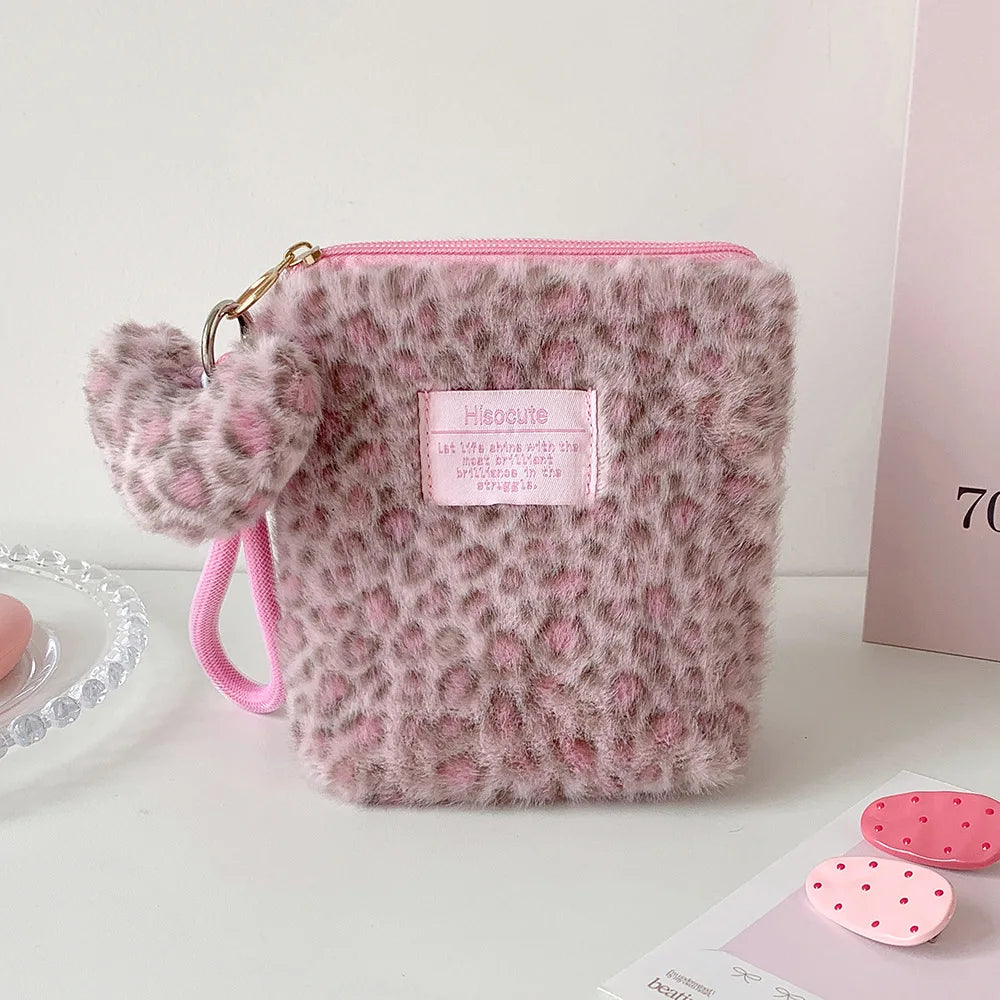 A fluffy pink leopard print cosmetic bag with a gold zipper and pink strap.