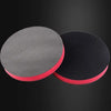 A pair of reusable magic clay pads for paint detailing, one gray and one black with a red rim.