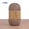 A ball of light beige cotton blend crochet yarn labeled in Japanese script on a wooden surface.
