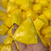 A hand holds a bright yellow, triangular fidget cube surrounded by other yellow cubes.