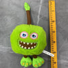 A bright green plush toy resembling a bird with large eyes and a toothy grin.