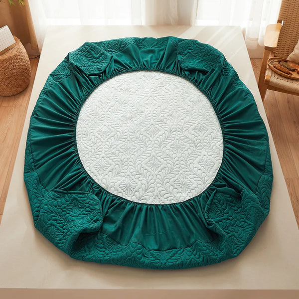 A teal quilted mattress protector with extra padding is shown on a white surface.