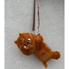 A fluffy brown teddy bear plush doll hanging by a strap against a gray background.