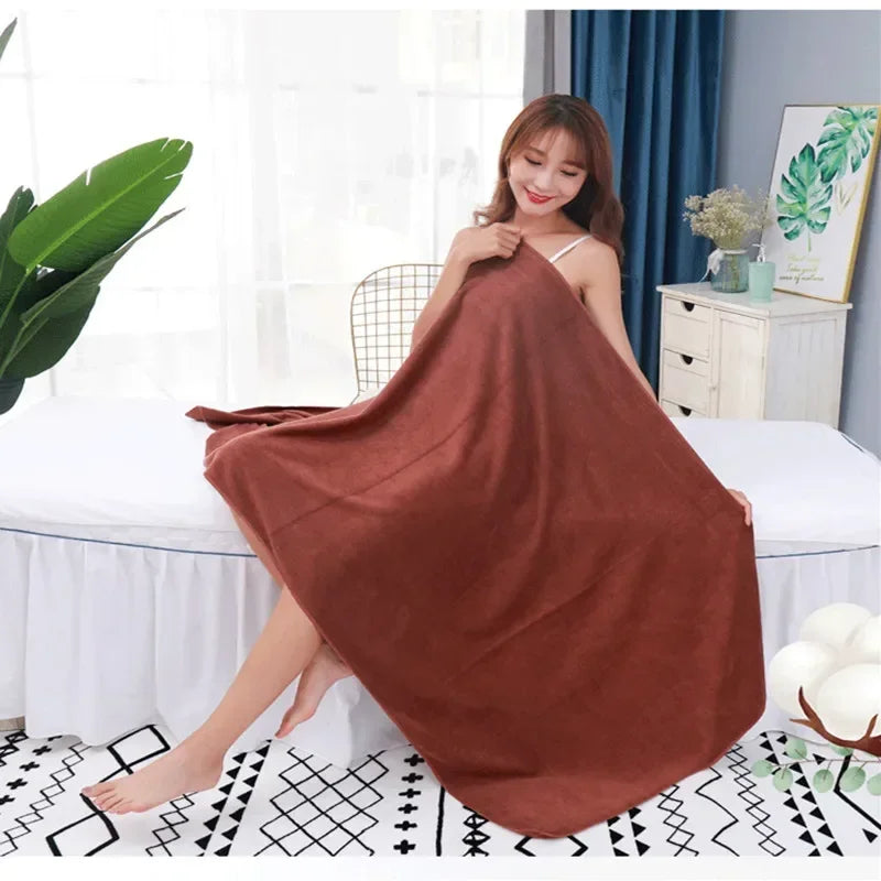 A woman models a large, rust-colored microfiber bath towel draped over her body in a bright room.