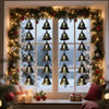 A vintage iron wind chime hangs in a window frame decorated with evergreen garlands and snow.