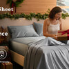 Eine Frau passt eine satinierte Bettdecke auf einem Bett mit natürlichem Licht und Grün im Hintergrund an.