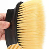 A hand holds a yellow detailing brush with black handle and soft bristles.