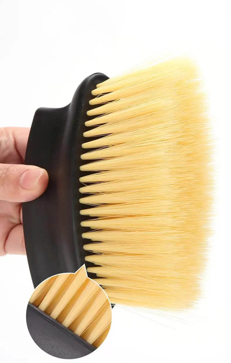 A hand holds a yellow detailing brush with black handle and soft bristles.