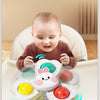 A baby is interacting with a set of spinning bath toys, including water wheels and a round toy.