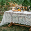 Elegant white lace tablecloth with French retro floral design set for an outdoor wedding or party.