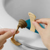 A hand is lifting a beige plastic toilet lid lifter from the rim of a white toilet bowl.