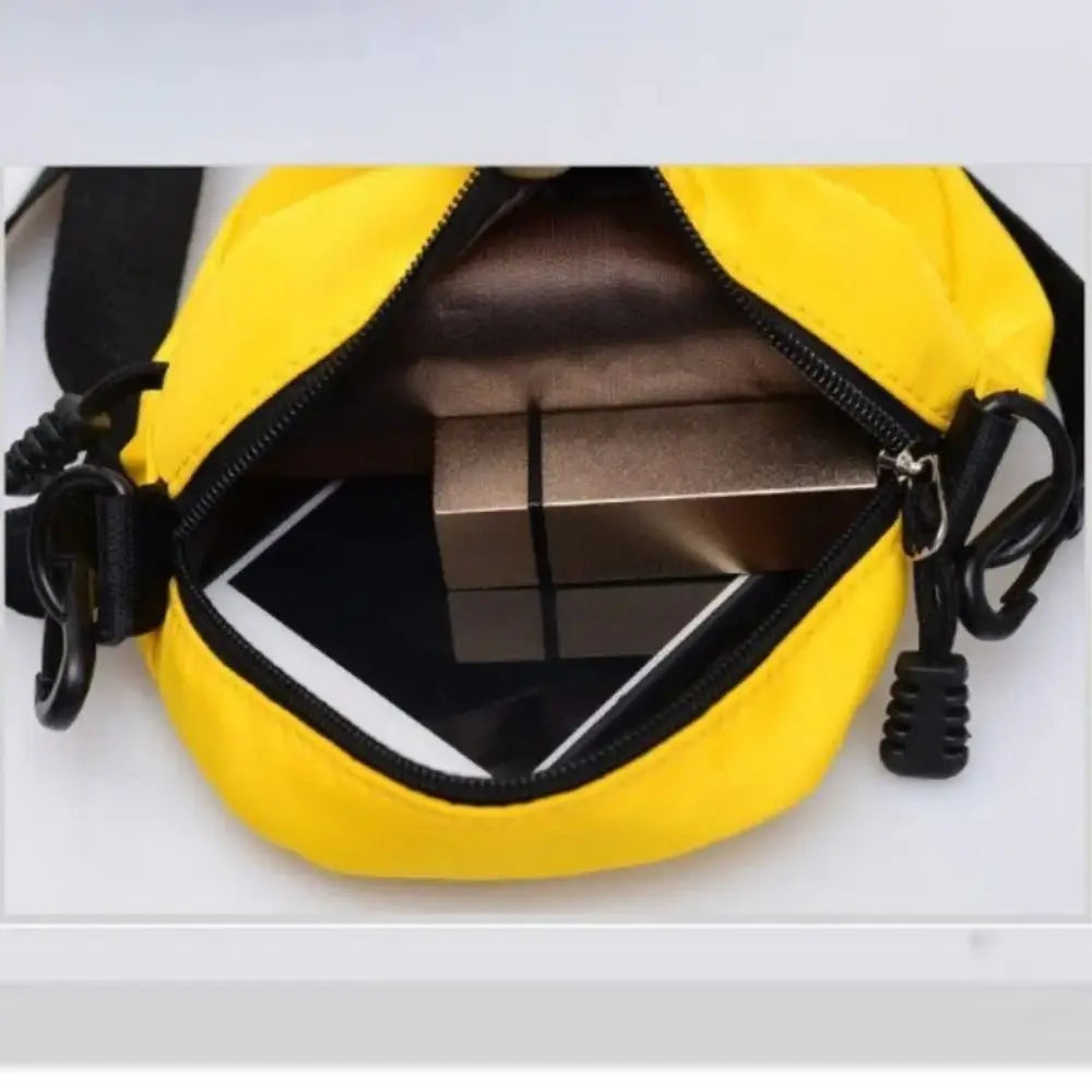 Yellow mini canvas crossbody bag with a black zipper and strap shown from the inside
