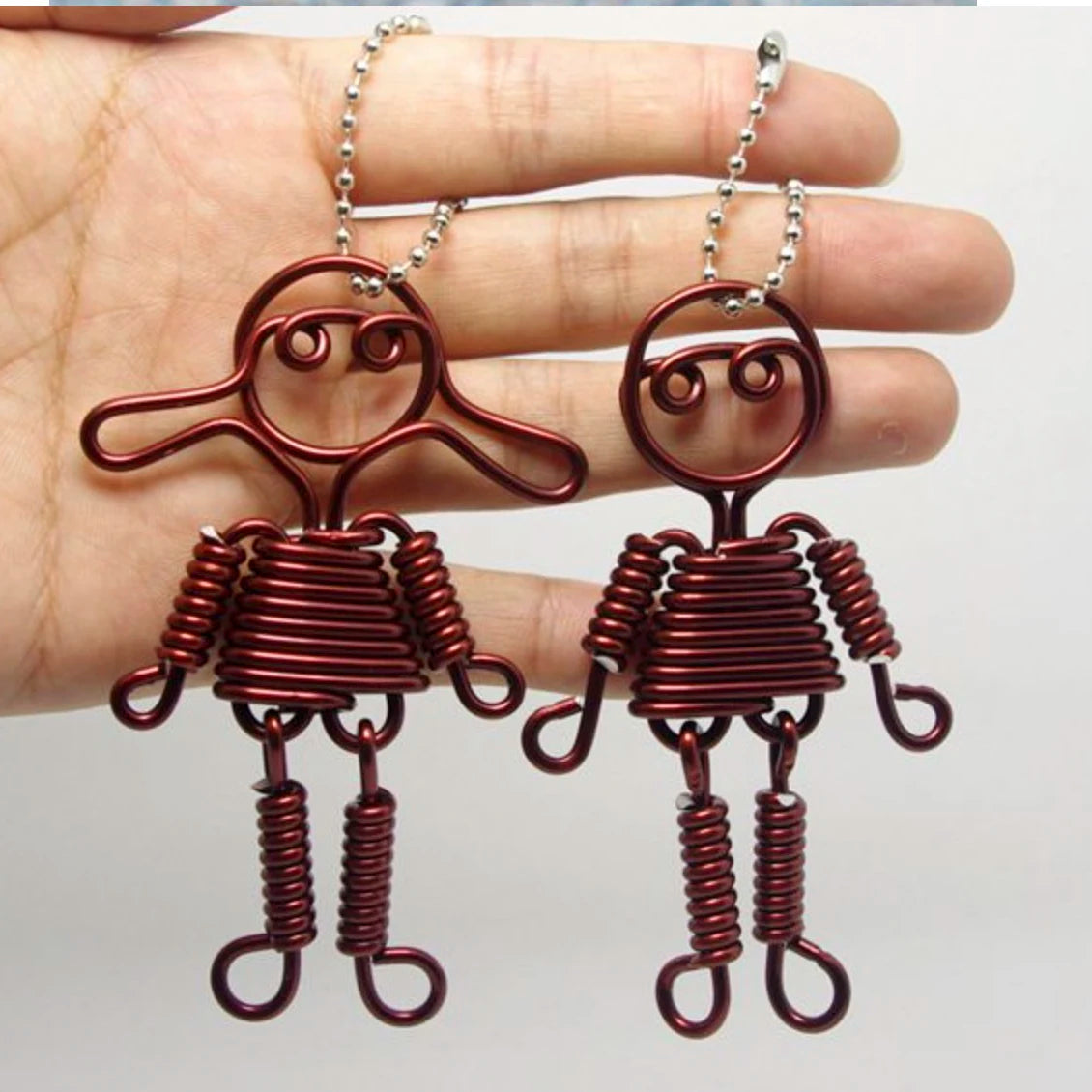 Pair of reddish-brown jewelry wire necklaces with decorative elements shown on a hand.