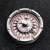 A close-up view of a metal fingertip gyro roulette dice with numbered faces resting on a dark surface.