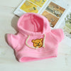 A pink knitted hoodie with a yellow bear charm and a matching yellow booklet in the background.