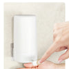 A hand is pressing the switch outlet on a white soap bar grinder and dispenser for no-contact press use.