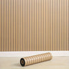 A roll of beige self-adhesive foam wall panels for decorative tiles resting on a light wooden floor.