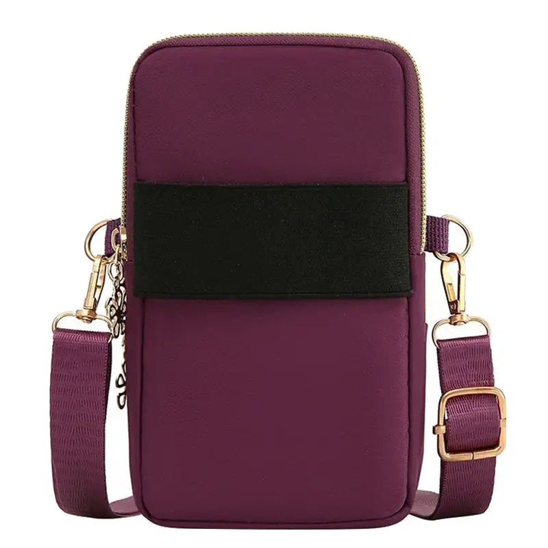 Bolso cruz impermeable de nylon morado intenso con correa negra y herrajes dorados.