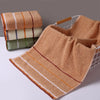 A set of three beige bath towels stacked next to a large, folded tan bath towel hanging on a wire rack.