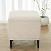 A beige geometric jacquard stretch ottoman cover placed on a wooden floor.