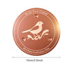 A round copper purification disk for a bird bath featuring a silhouette of a bird.