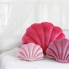 A collection of pink and magenta velvet shell print throw pillows resting on white bedding.
