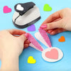 Hands are using a heart-shaped paper punch set for crafting on a light blue background.