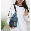 A woman wearing a light gray sweatshirt holds a colorful leaf print sling crossbody bag.