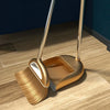 A golden broom and dustpan set with a floor wiper resting on a wooden floor.