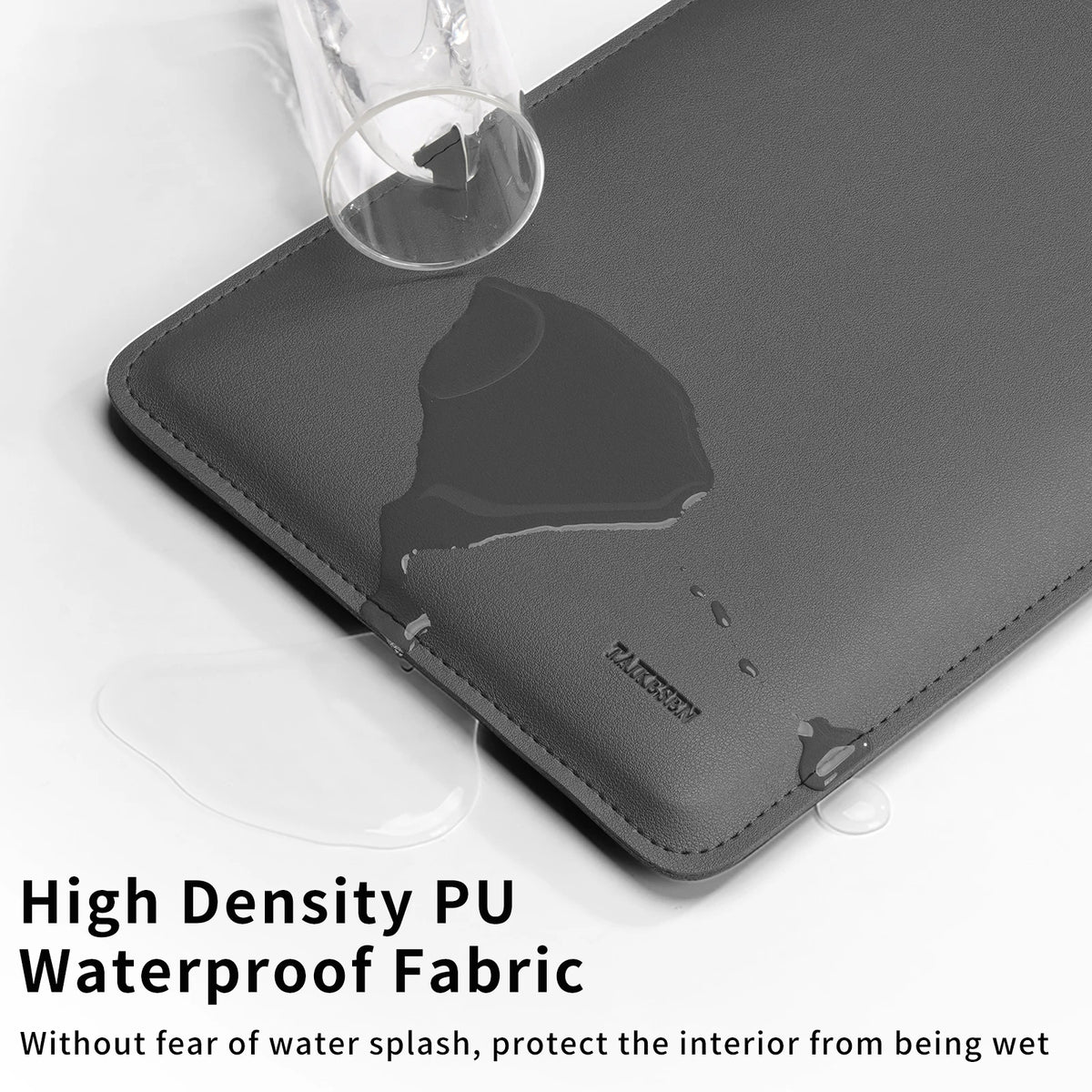 A dark gray PU fabric laptop sleeve is shown with a glass resting on top, highlighting its waterproof fabric quality.