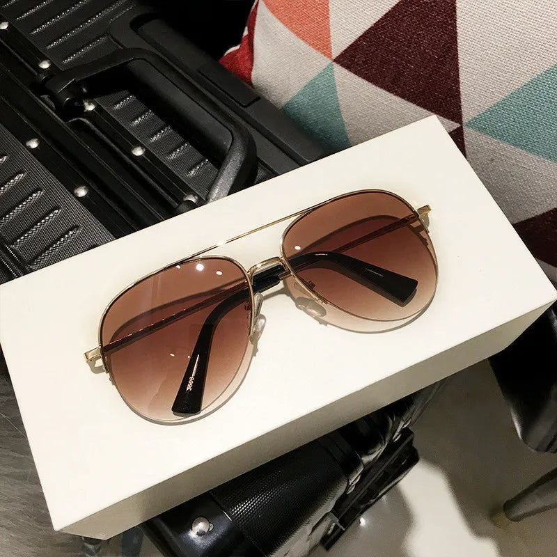 Paar klassischer Aviator-Sonnenbrille mit braunen Linsen und goldenen Akzenten auf einer weißen Box.