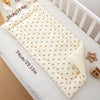 A cream-colored padded baby stroller seat cushion with a heart pattern is shown on a white surface.