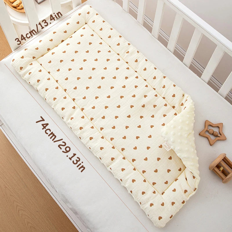 A cream-colored padded baby stroller seat cushion with a heart pattern is shown on a white surface.