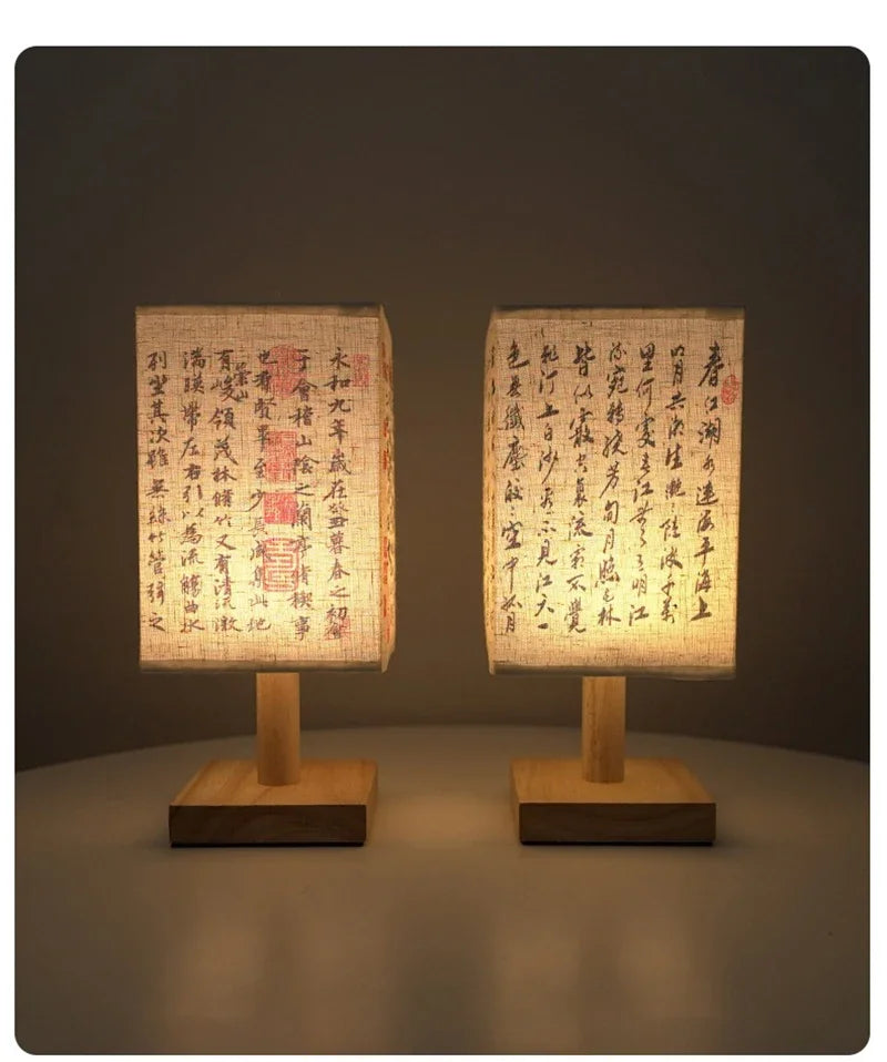 A pair of Chinese style table lamps with linen shades and wooden bases, illuminated against a dark background.