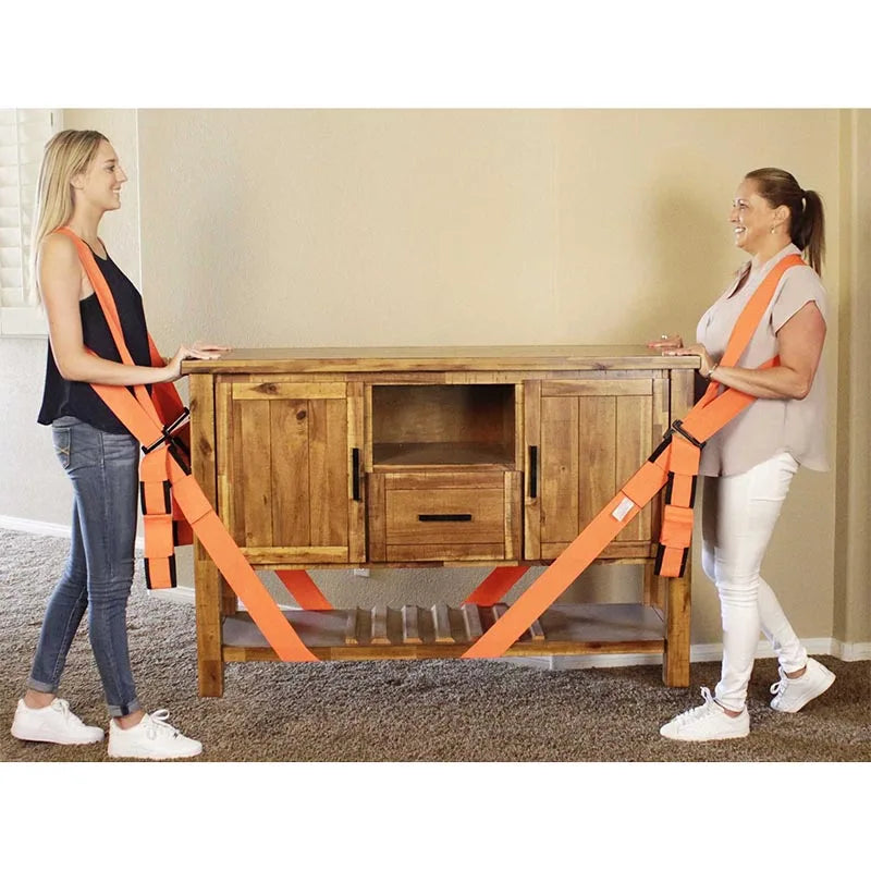 Two women demonstrate adjustable furniture moving straps with shoulder pads on a wooden table.