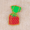 A shiny red strawberry enamel pin with a green stem and gold detailing.