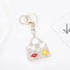 Gold chain keychain featuring a crystal rhinestone handbag charm with a white and yellow design